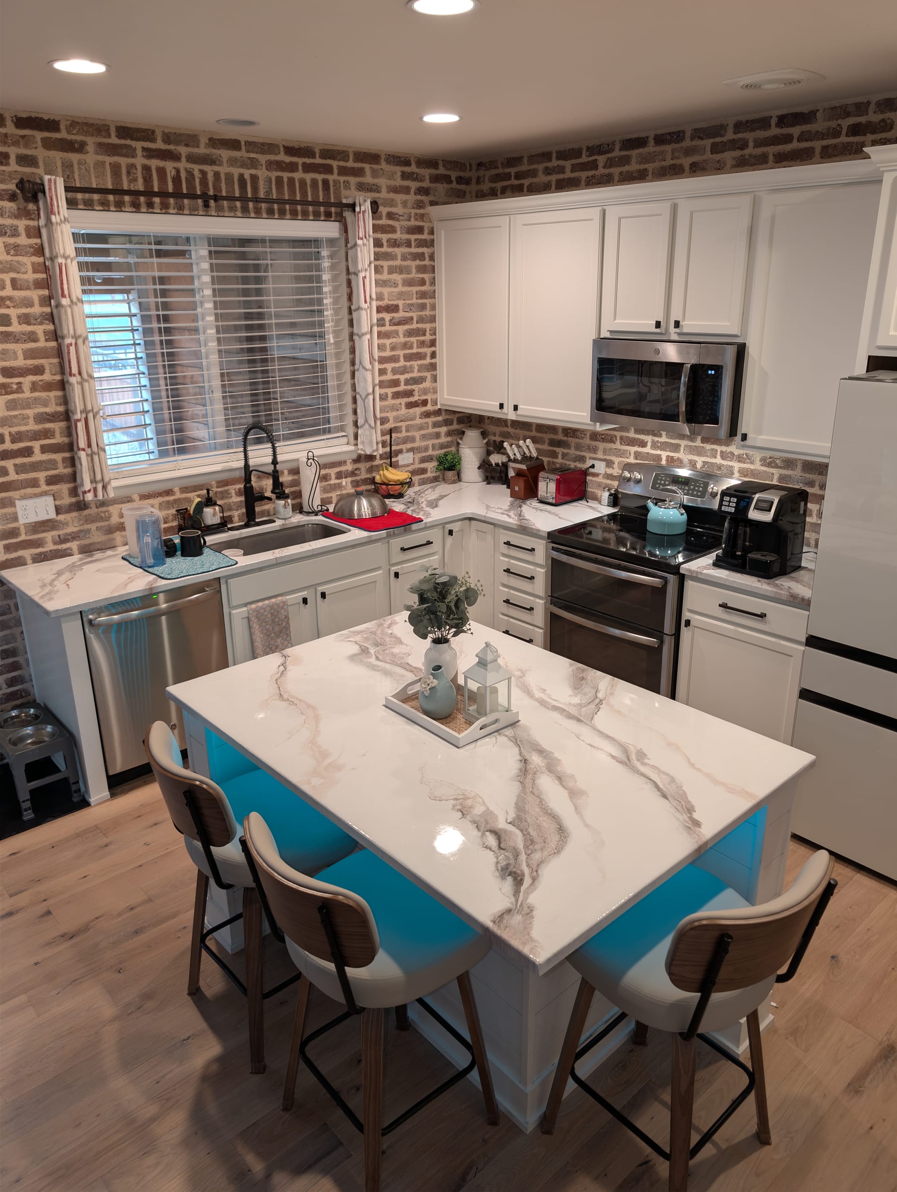 Cream and tan marble-effect epoxy kitchen by Ray Sample, with island and brick backsplash